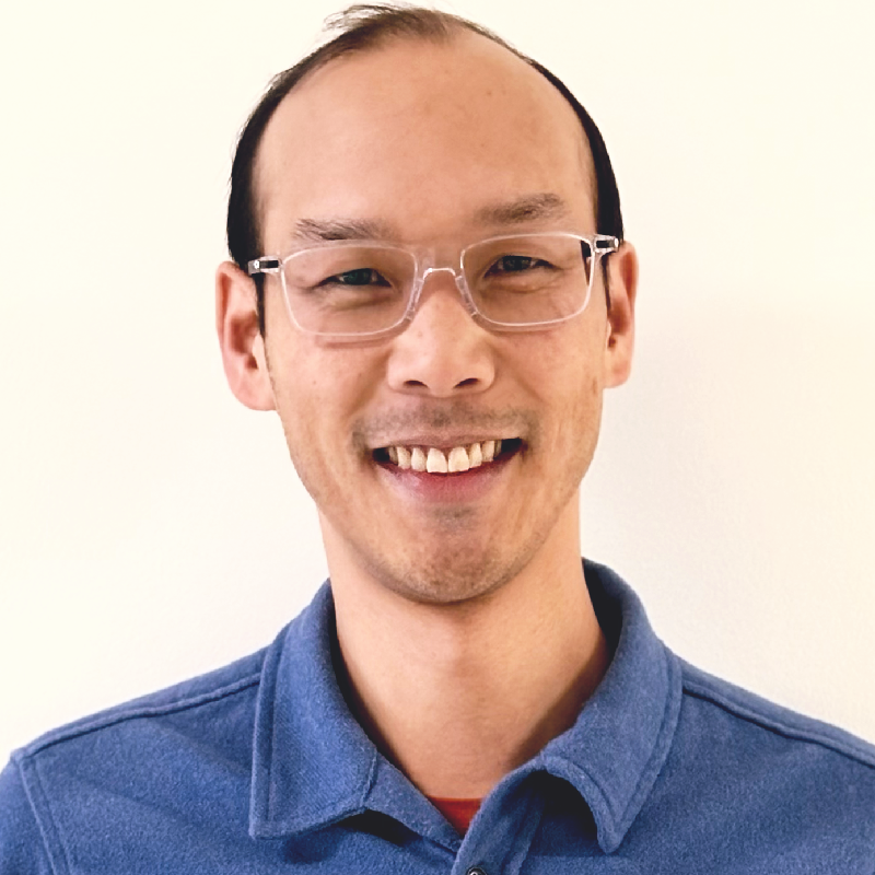 Michael Li — a smiling Asian man with short dark-brown hair and clear-framed glasses wearing a denim-blue collared shirt